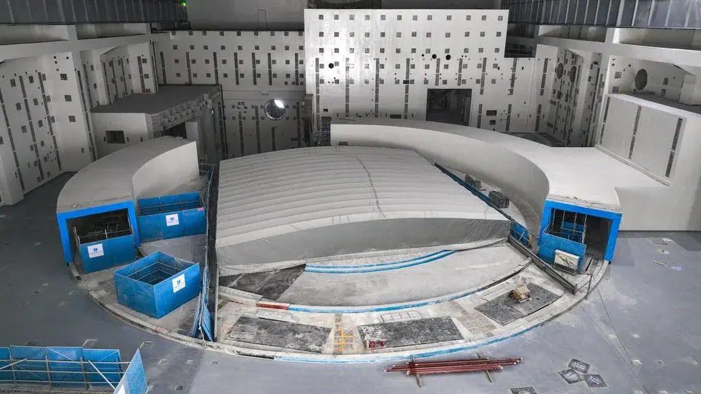 The circular hall of a fusion machine under construction, with blue equipment cabinets around its base